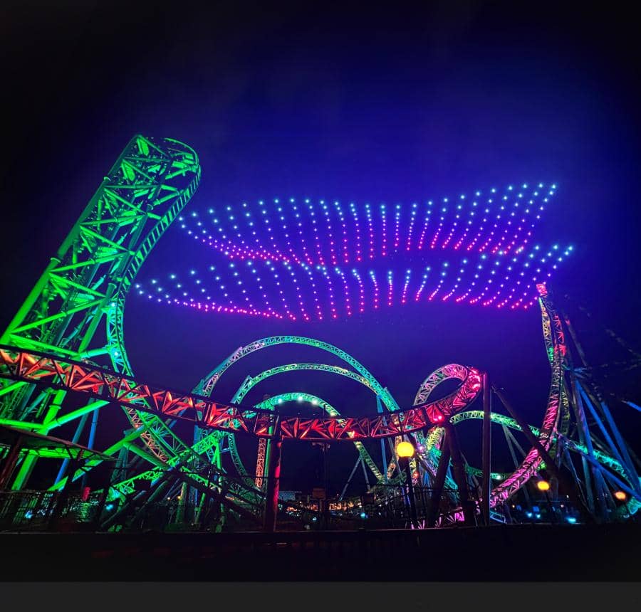 Drones fill the night sky in front of the Monster Roller Coaster at Adventureland 